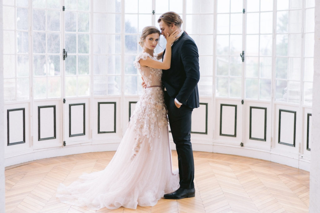 couple de mariés devant une fenêtre mis en scène par la wedding planner Amélie Pichon Weddings