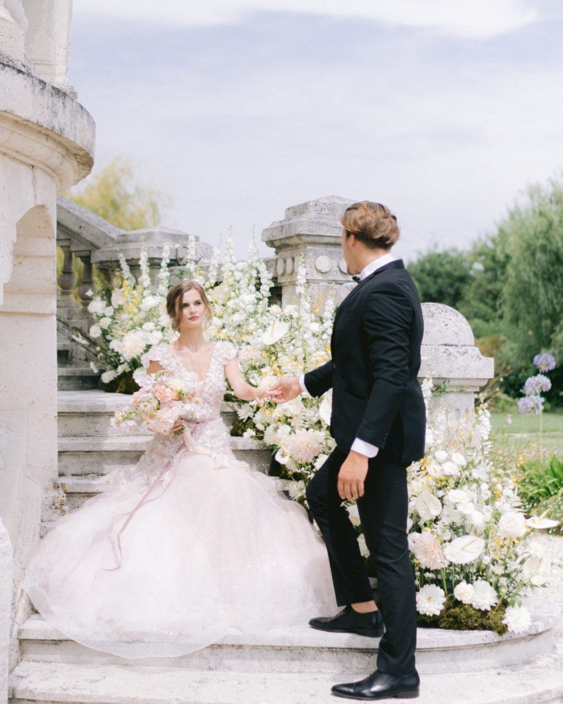 mariee et mari dans un escalier fleuri mis en scène par la wedding planner Amélie Pichon Weddings
