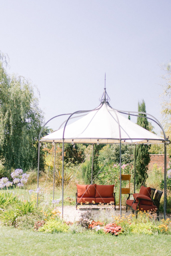 Jardin fleuri avec une arche et des canapés mis en scène par la wedding planner Amélie Pichon Weddings
