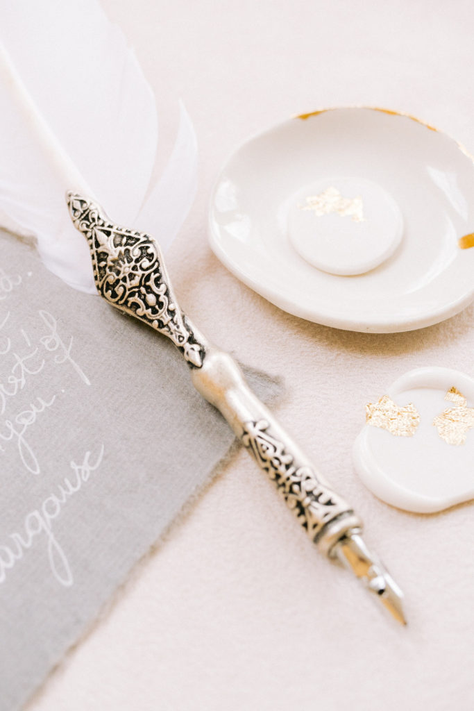 Flatlays plume et de sceau de cire blanc et or mis en scène par la wedding planner Amélie Pichon Weddings