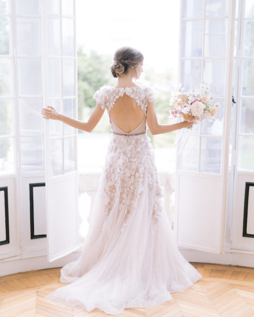 mariée en robe vue de dos devant une fenêtre mis en scène par la wedding planner Amélie Pichon Weddings