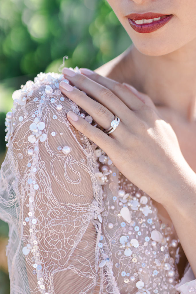 Main mariée posée sur son épaule montrant les détails de la robe et de son alliance mis en scène par la wedding planner Amélie Pichon Weddings