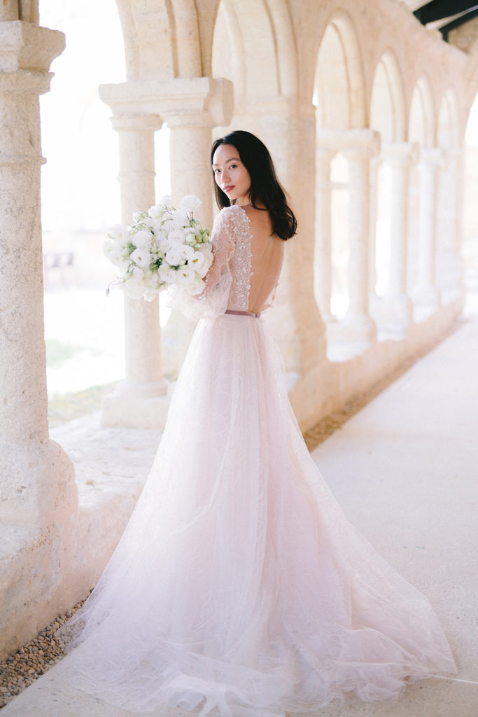 Mariée robe tenant son bouquet fleurs blanches mis en scène par la wedding planner Amélie Pichon Weddings